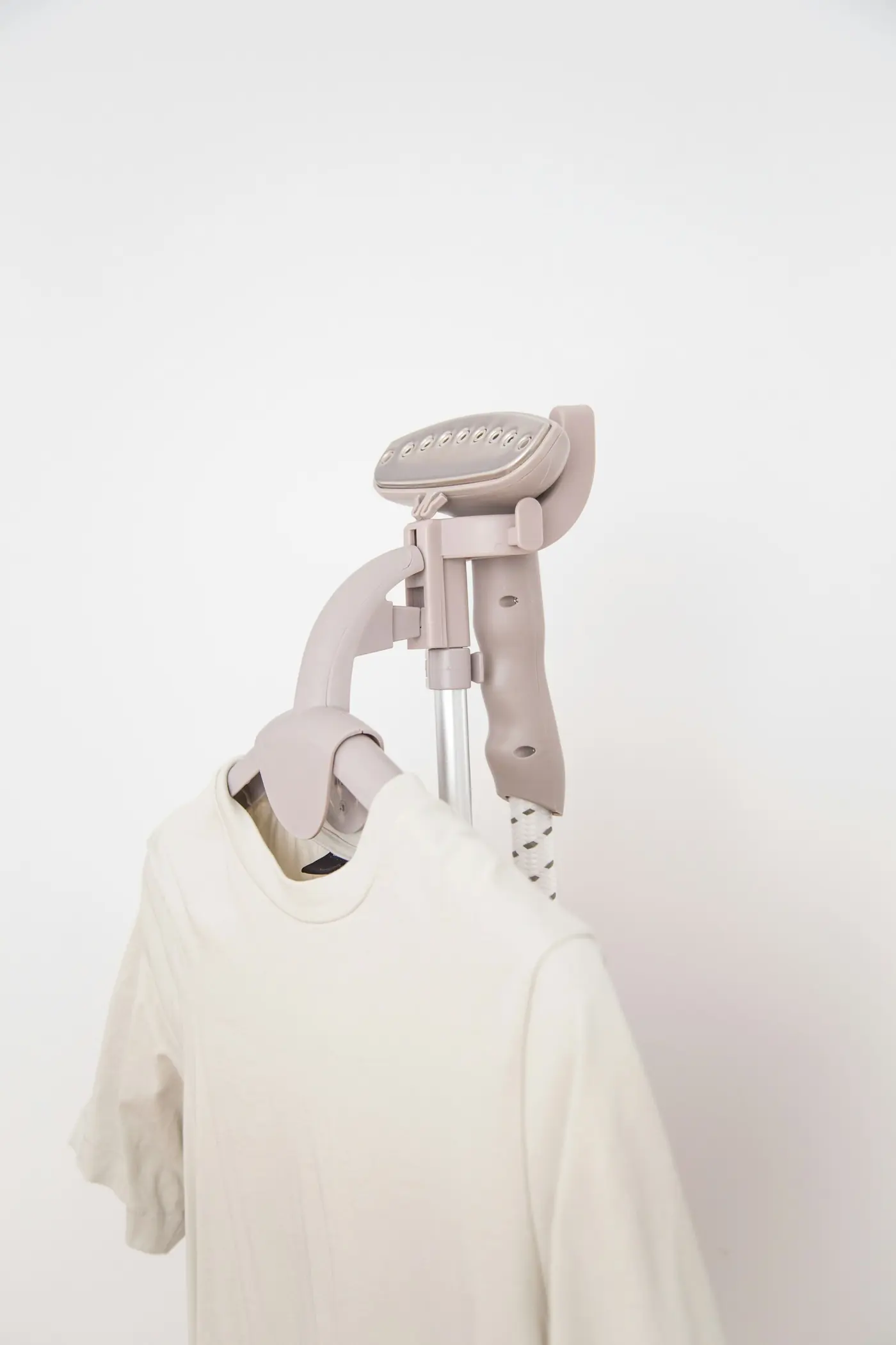 A garment steamer beside a white cotton t-shirt on a hanger